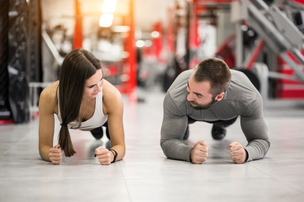 El hombre y la mujer realizan el ejercicio Plank, diseñado para todos los grupos musculares